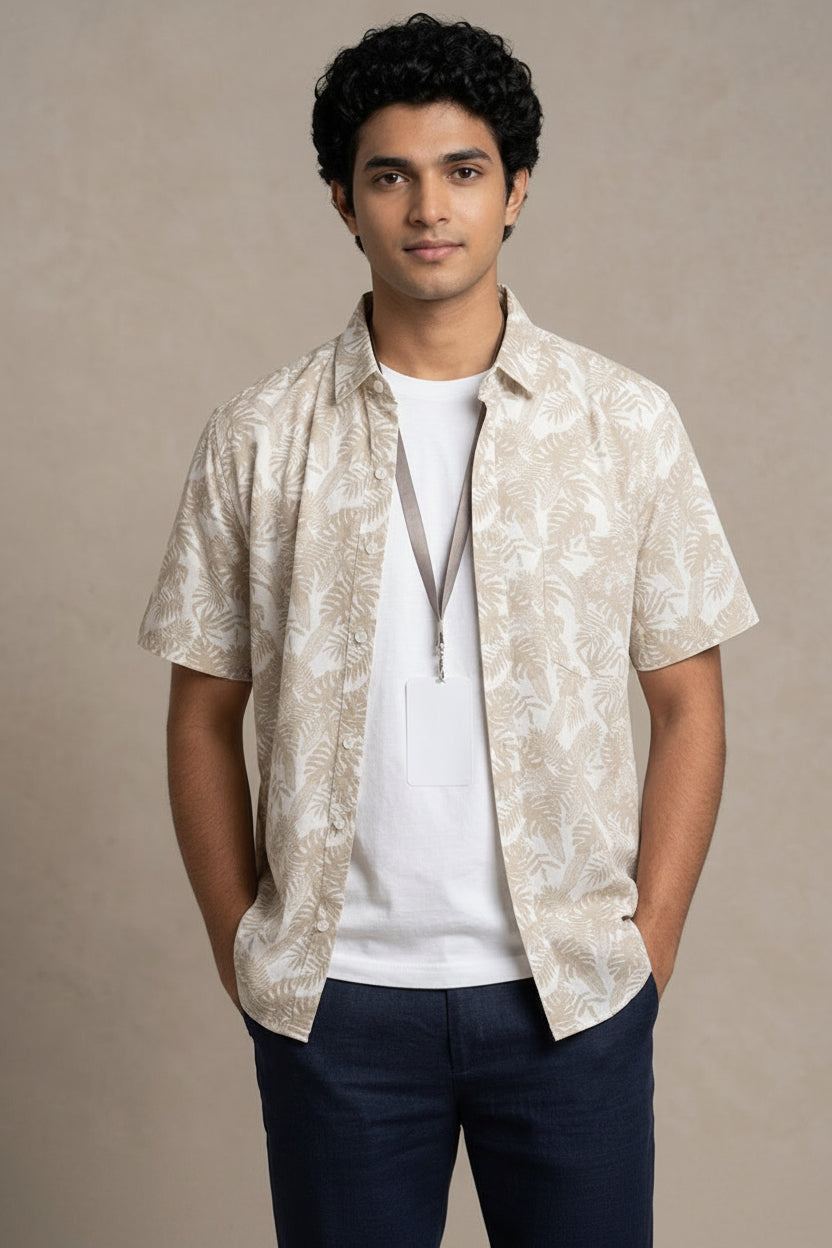 Man wearing a patterned beige shirt over a white COTTON shirt with navy pants on a beige background
