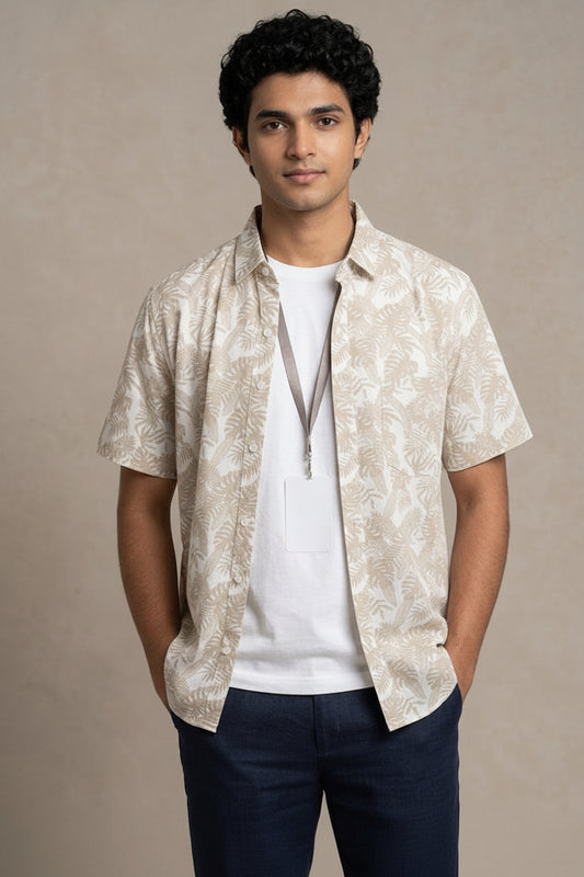 Man wearing a patterned beige shirt over a white COTTON shirt with navy pants on a beige background