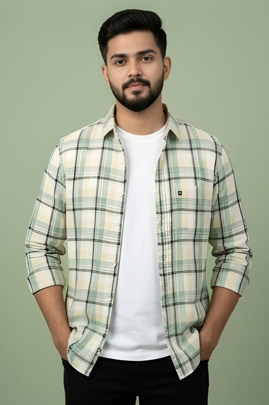 Man wearing a plaid shirt over a white t-shirt against a green background